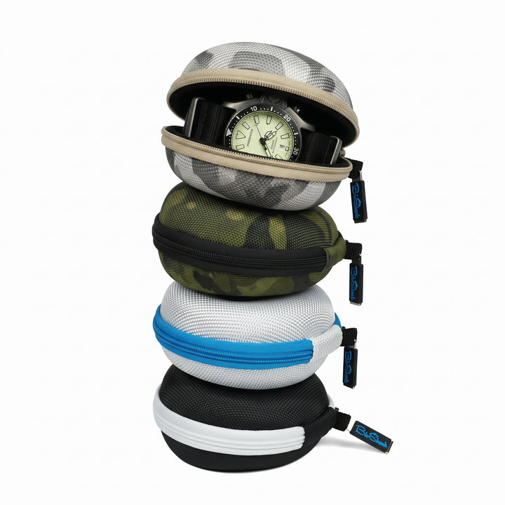 Four round zippered watch storage cases stacked vertically on a white background, with a watch partially visible inside the top case. The cases come in camouflage and solid color options: gray and black camo, olive green camo, white and green camo, and black and white.