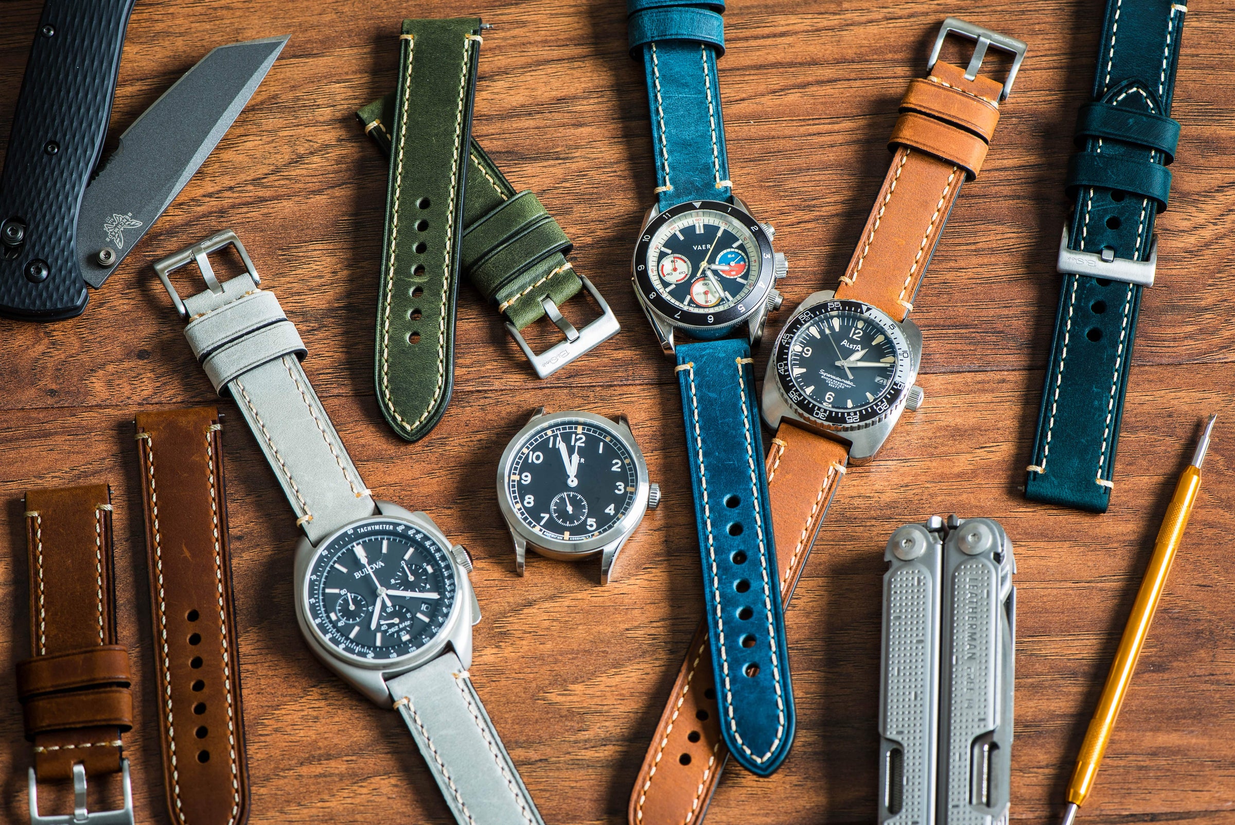 Collection of watches with various straps on a wooden surface