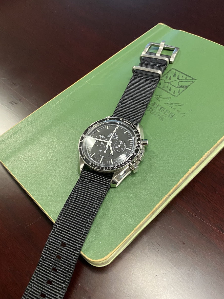 Wristwatch with black strap on a green book