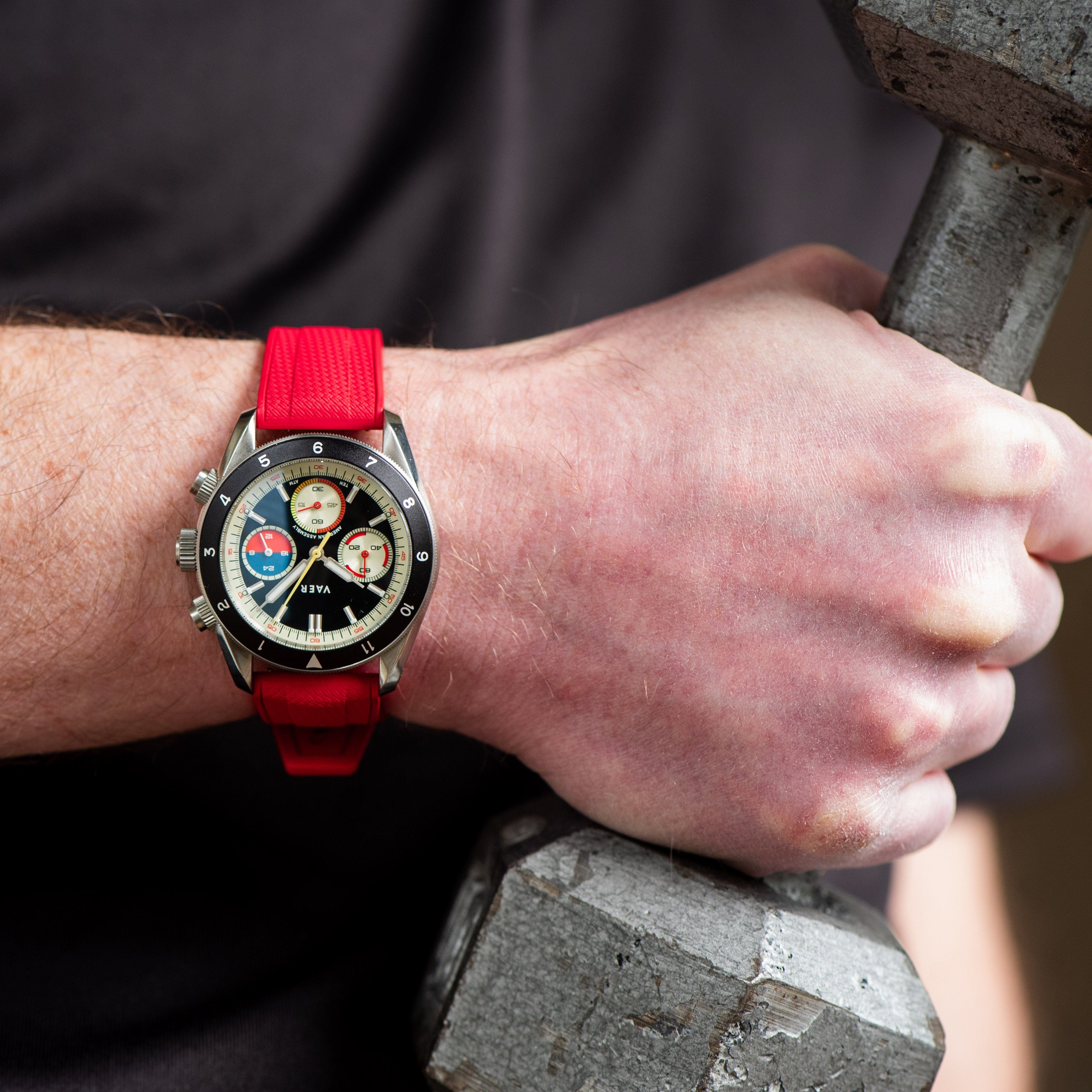 Person wearing a watch with a red rubber watch strap holding a dumbbell.